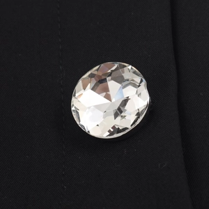 Macro detail of faceted crystal button and twill texture on black top fabric