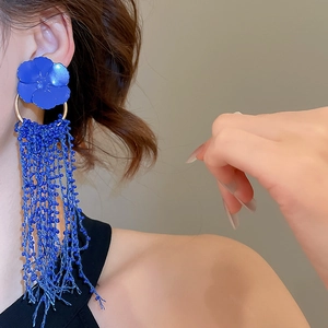 Close-up of elegant Klein Blue flower earrings with long silk tassels and gold metal hoop