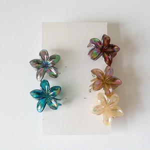 Close-up of five-petal flower hair claws with a shimmering iridescent aurora finish