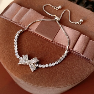Macro shot of a silver bow bracelet with clear zircons on a luxury ribbon gift box