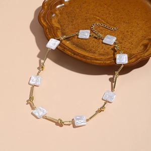 Detail of baroque pearl necklace with golden knotted links and white square pendants