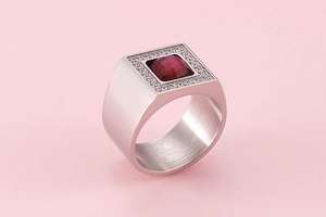 Macro detail of silver stainless steel ring featuring a square red gemstone and cubic zirconia