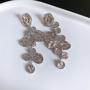 Détail macro de boucles d'oreilles argentées en disques de métal martelés irréguliers