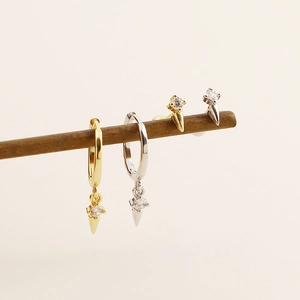 Detail of silver and gold rivet hoop earrings and studs with zircon on a wooden branch