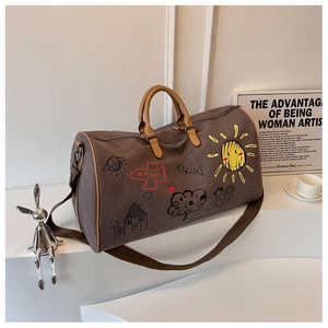 Detail of large brown canvas travel bag featuring colorful artistic graffiti patterns