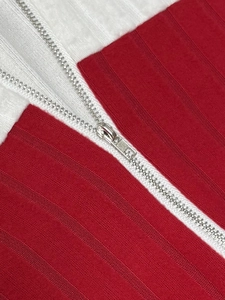 Detailed close-up of red and white ribbed knit fabric with a silver metal zipper