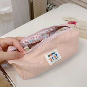 Close-up of pink canvas stationery pouch showing floral lining and zip interior