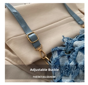 Close-up of the adjustable golden buckle and blue denim strap with fringe detail