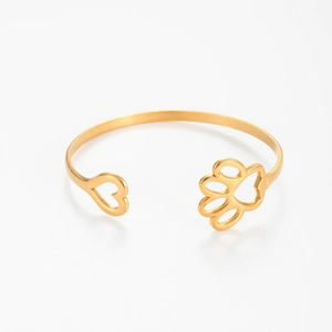 Gold open oval bracelet with hollow heart and paw print design on white background