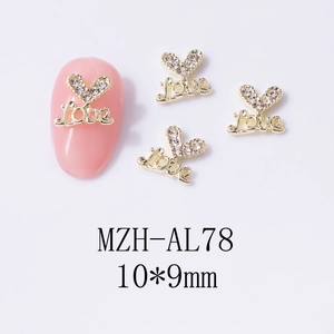 Vista macro di ciondoli per unghie a cuore dorato con strass e incisione Love 10x9mm