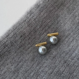 Nahaufnahme von Vintage-Perlenohrringen mit Goldstegen auf dunkelgrauem Strickstoff