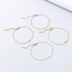 Detail of beaded cross bracelets in gold and silver steel with pink and white beads