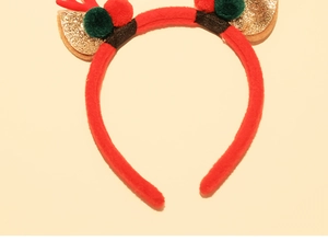 Detail of red plush Christmas headband with golden sequin reindeer antlers and pom poms