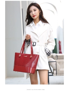 Detail of red crocodile pattern patent leather tote bag with gold logo and buckles