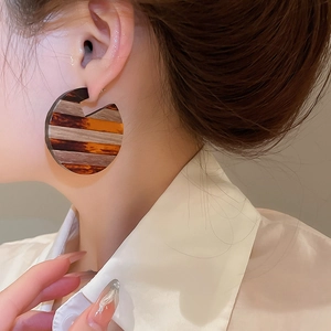 Detailed view of large retro tortoiseshell resin C-shaped hoop earrings on model
