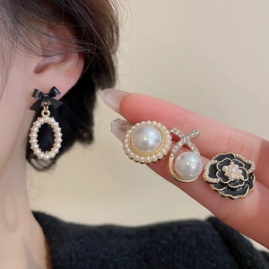 Detail showing classic camellia flower and black bow pearl earrings on a model