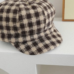 Retro checkered tweed newsboy cap for girls on a minimalist white display stand