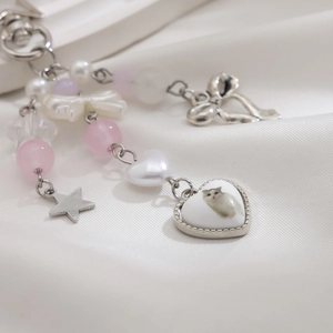 Macro detail of strawberry bow keychain with cat heart pendant on white silk fabric