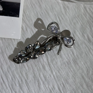 Detail of silver metal bow hair clip with sparkling clear and grey rhinestones