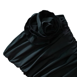 Detail of a black ruched strapless dress featuring a large 3D fabric rose embellishment