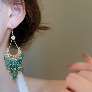 Detailed close-up of bohemian water-drop fringe earrings with emerald green crystals