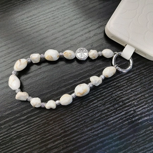 Detailed macro of bohemian beaded phone strap with vintage religious silver medal