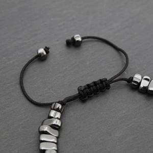 Macro shot of adjustable braided rope knot and dark grey metallic beads on the bracelet