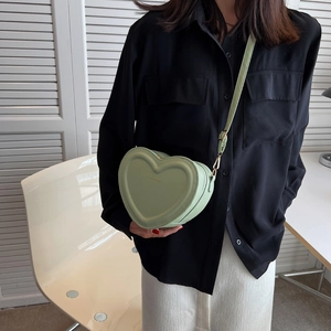 Dettaglio borsa a tracolla verde chiaro a forma di cuore con hardware dorato e trama in pelle
