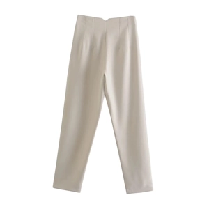 Detailed view of beige high-waisted trousers with pleated texture and straight leg cut