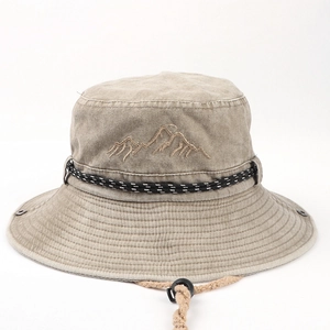 Detailed close-up of khaki canvas bucket hat with mountain embroidery and windproof cord