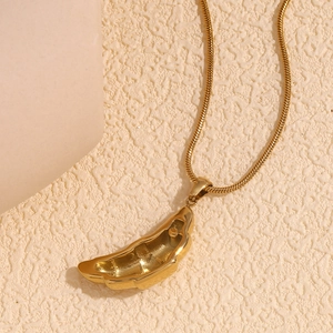 Close-up of a vintage 18K gold plated croissant horn pendant on a sleek snake chain