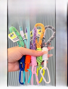 Close-up of woven paracord keychains with colorful D-rings and fabric letter tags