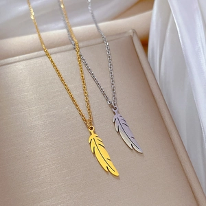 Détail des colliers en acier titane or et argent avec pendentifs en forme de feuille