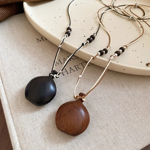 Close-up of retro wooden pendant necklace showing natural wood grain and woven rope details