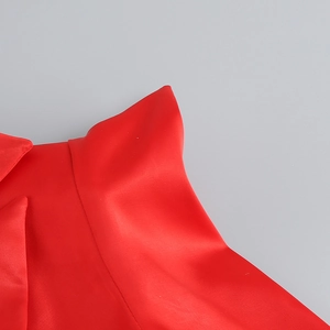 Close-up of red satin fabric folds on a tight V-neck party dress showing material detail