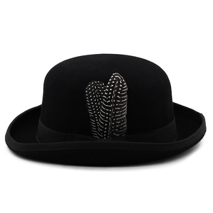 Macro detail of black wool bowler hat with satin ribbon and spotted feather decoration