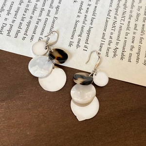 Detail view of multi-layered acrylic geometric tassel earrings on vintage book background