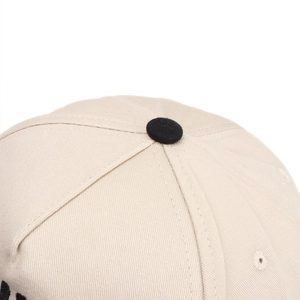 Close-up of baseball cap top crown with black button and beige cotton twill fabric