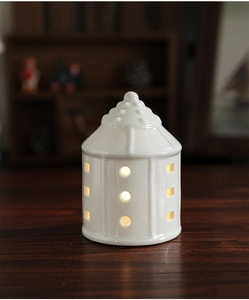 Detail of white ceramic Christmas house light with warm LED glowing through holes