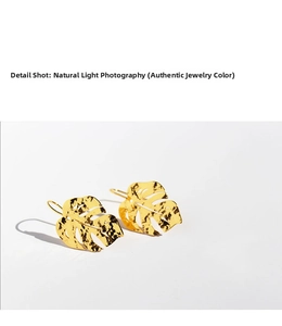 Detail view of gold-plated leaf earrings with hammered texture and hook design