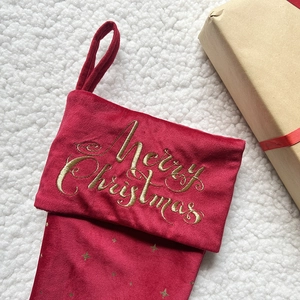 Detail of red velvet Christmas stocking with gold Merry Christmas embroidery and star patterns