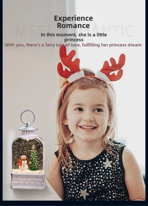 Close-up of a silver Christmas lantern with a snowman, festive tree, and glitter snow