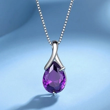 Macro shot of a purple pear-cut gemstone pendant on a fine silver necklace chain