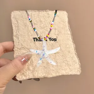 Detailed close-up of a handmade starfish pendant with colorful beads on a cord necklace