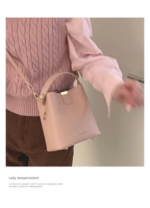 Detail view of pink bucket bag with brand logo and adjustable leather shoulder strap