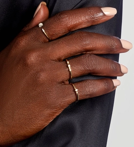 Close-up of sparkling zircon gold rings on hand over dark silk background