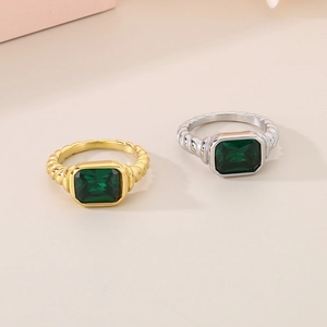 Detail of gold and silver rings with emerald green rectangular stones and twisted band