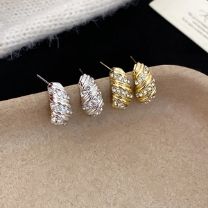 Detailed macro view of spiral textured earrings set with sparkling crystals in gold and silver