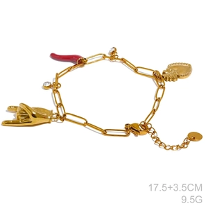 Detailed shot of a gold charm bracelet with red chili, heart, and rock gesture charms
