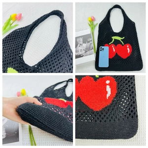 Detail of black knit tote bag showing hollow mesh pattern and red cherry embroidery